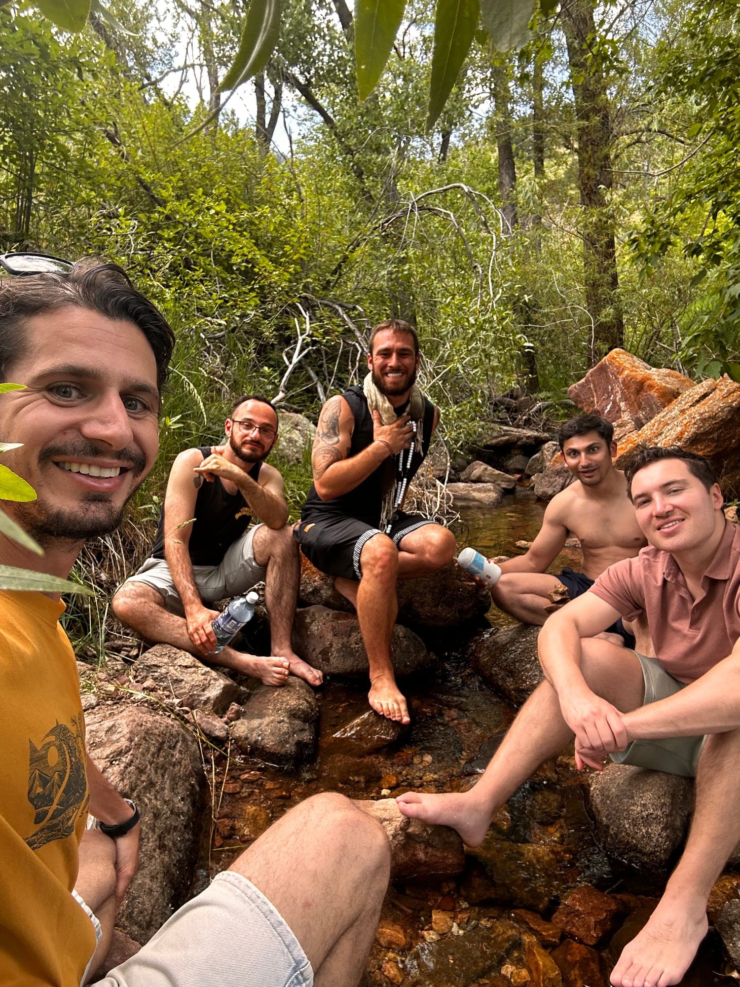 Men from a retreat resting together at a creek after a hike