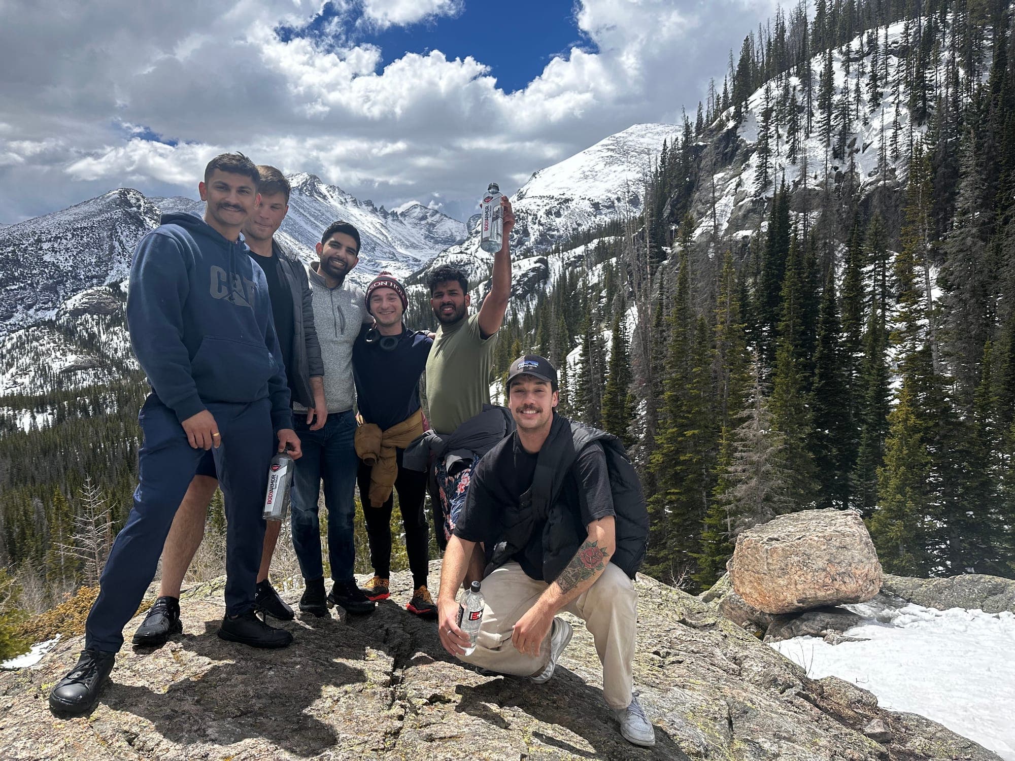 Six retreat participants together on a rocky overlook surrounded by snowy mountains