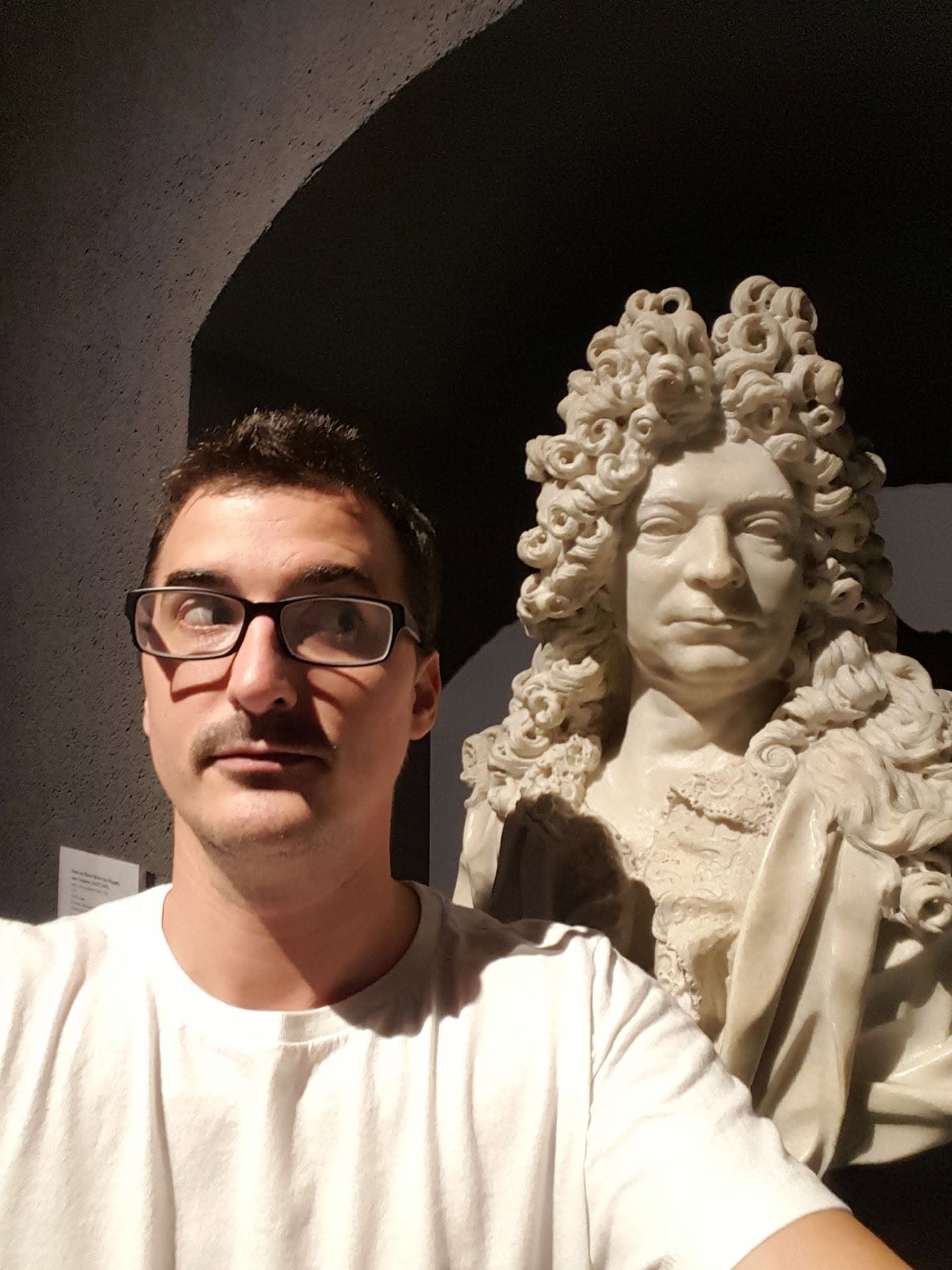Tom wearing glasses beside a sculpted bust at the Musée d’Aquitaine in Bordeaux