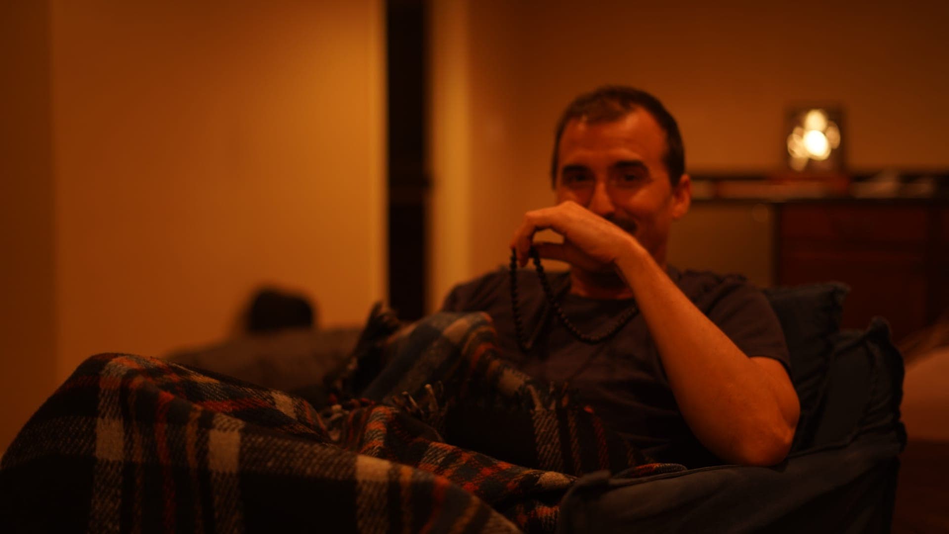 Thomas Whigham sitting with mala beads in warm lamplight