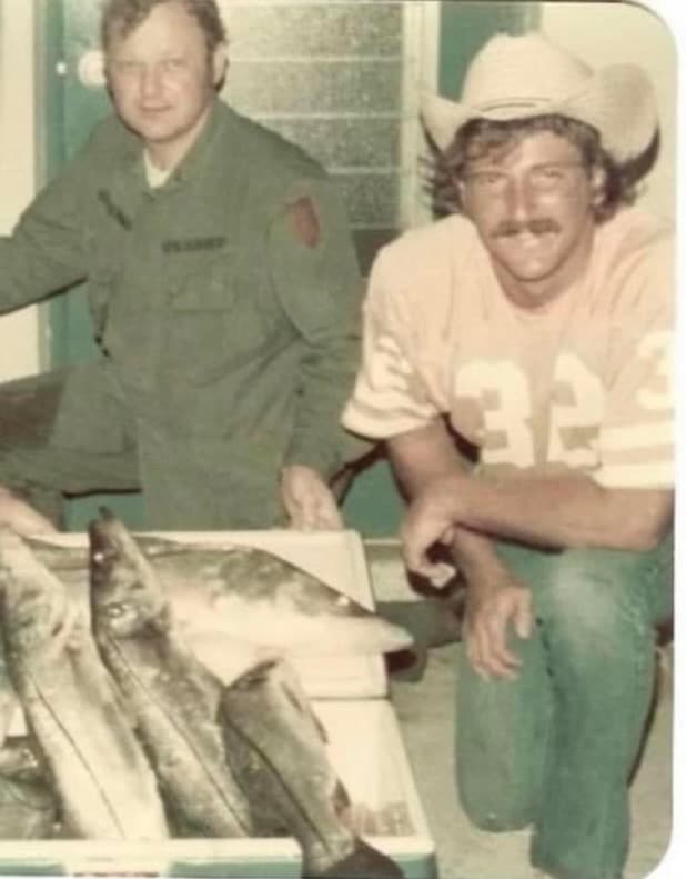 Old snapshot of Thomas Whigham's father and another man, in army fatigues and a cowboy hat, posing behind caught fish.