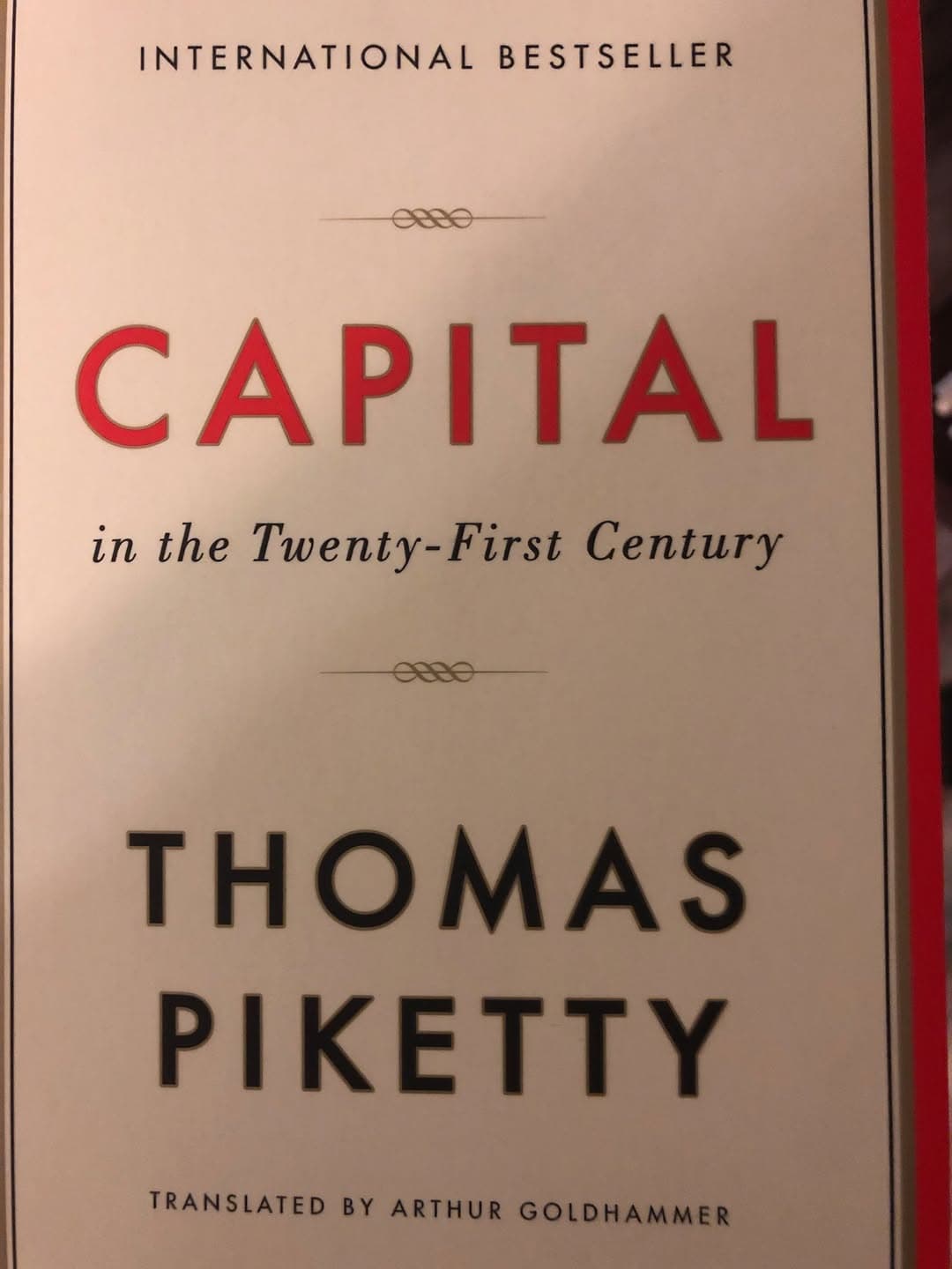 Book cover reads: "International Bestseller. Capital in the Twenty-First Century. Thomas Piketty. Translated by Arthur Goldhammer."