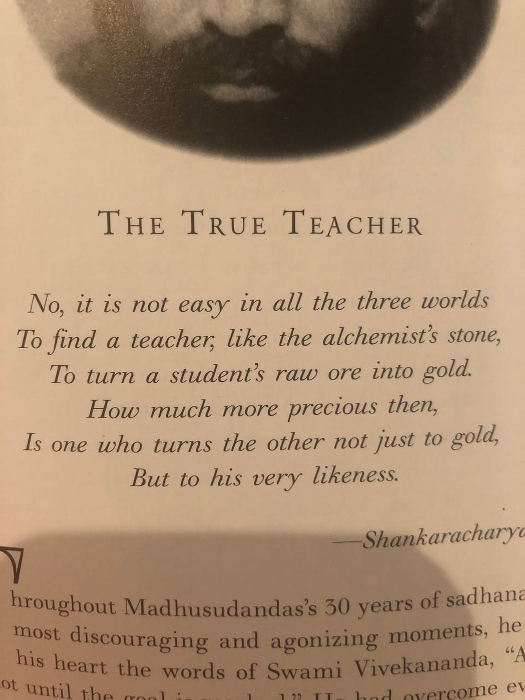 Book page headed "The True Teacher" with a Shankaracharya verse: "No, it is not easy in all the three worlds to find a teacher, like the alchemist's stone, to turn a student's raw ore into gold."