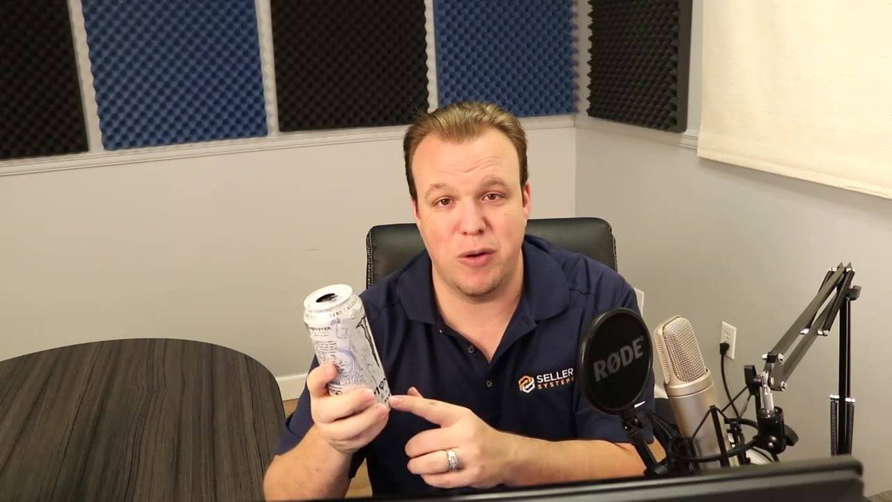 A man in a navy polo holds up a small canister beside a Rode microphone in a foam-paneled studio.