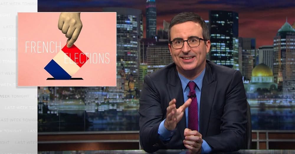 A TV host in glasses and a dark suit gestures at his desk beside a graphic reading "French Elections."
